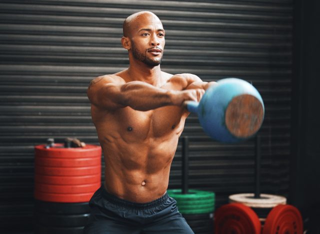 fitt férfi kettlebell hintákat csinál, testrekompozíciós gyakorlatok fogalma