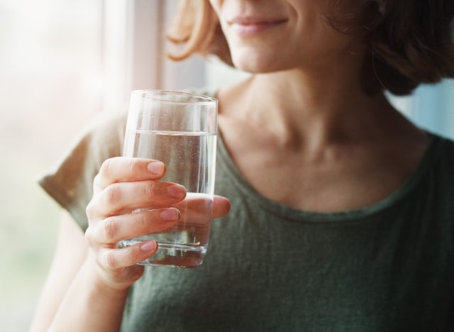 közeli nő gazdaság víz pohár, koncepció a hasi zsír veszteség tippek a nők számára