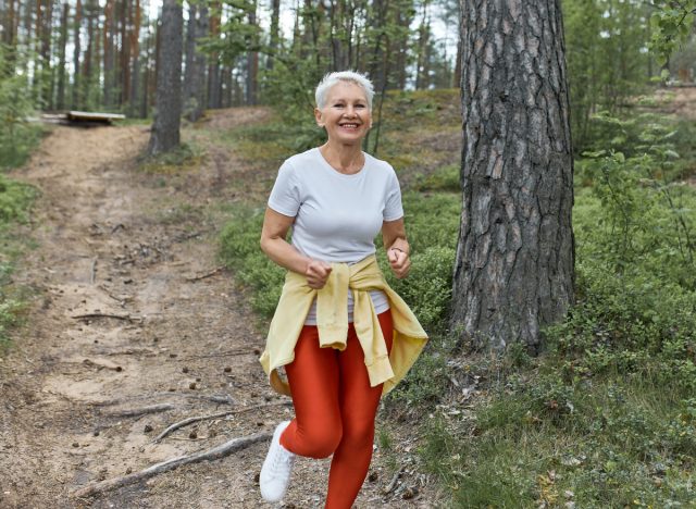 boldog érett nő az erdőben, aki bemutatja az öregedés lassító szokásait