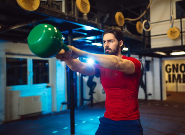 fitt férfi kettlebell hinták az edzőteremben, koncepció a hibák kettlebell