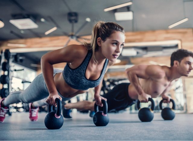 fitnesz pár kettlebell fekvőtámaszt végez zsírégető gyakorlatokkal, hogy lefogyjon az edzőteremben