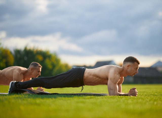 érett, izmos férfi csinál deszkát szabadban csoportos fitnesz órán