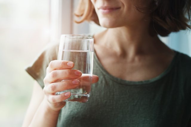 egészséges, gyönyörű fiatal nő gazdaság pohár vizet