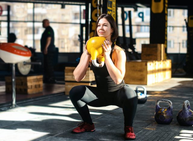 nő csinál kettlebell serleg guggolás súlyzós edzés gyakorlatok fogyás az edzőteremben