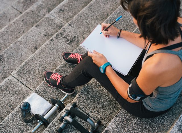 nő, aki nyomon követi fitnesz- és fogyási céljait a naplóban, fogalma arról, hogyan veszítheti el a nagy hasát a célok kitűzésével