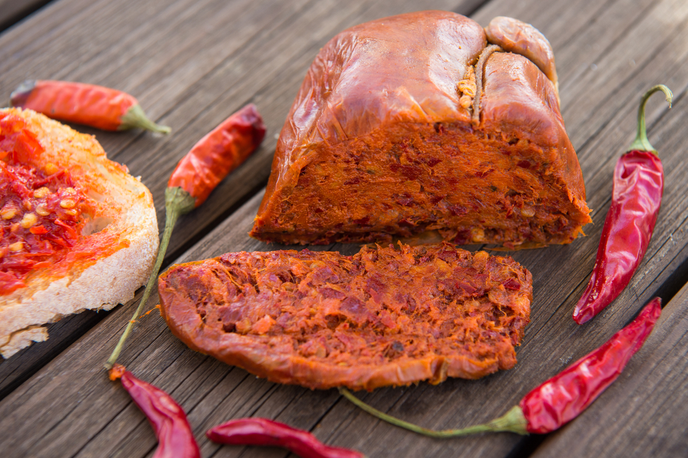 'Nduja néhány darab csípős paprikával együtt