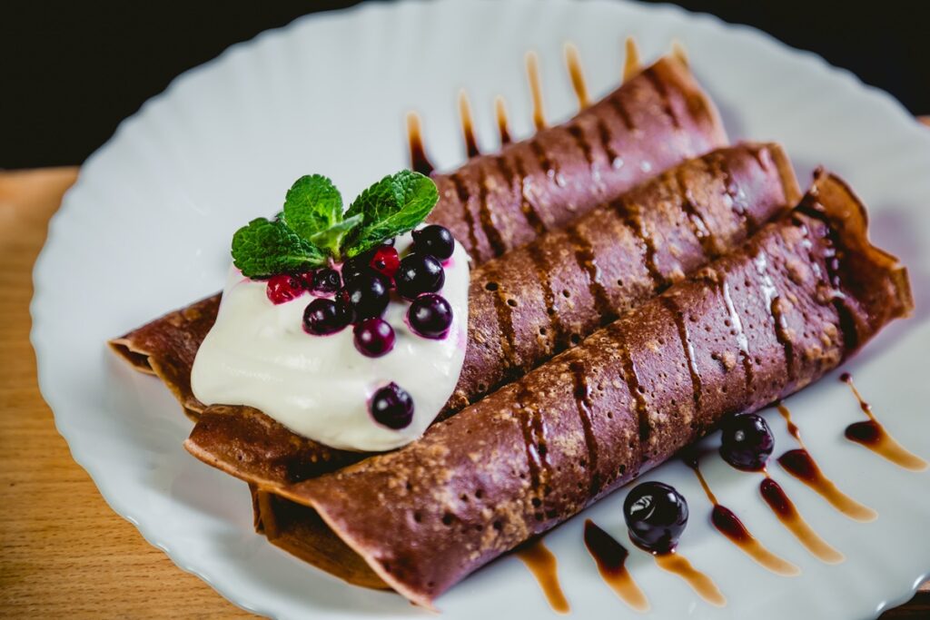 Tiramisu palacsinta tányéron, tejszínhabbal, mentával és gyümölccsel díszítve