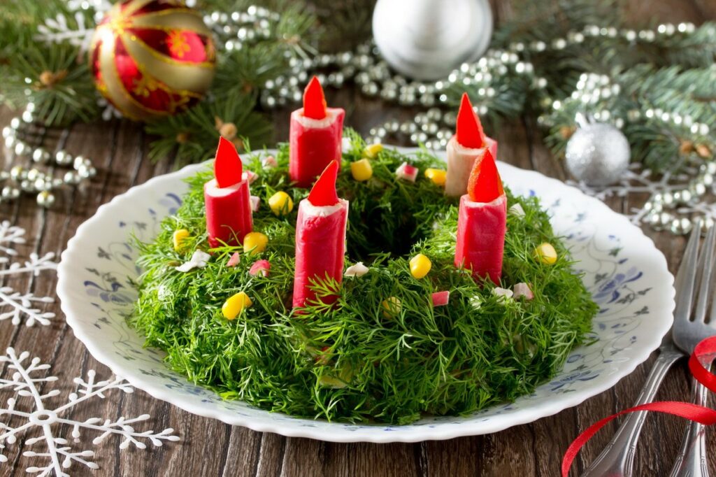 Piros gyertyákkal díszített zöld saláta fehér tányéron
